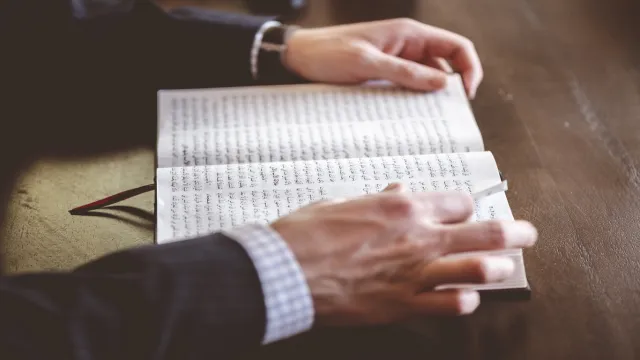 Mãos segurando um livro aberto