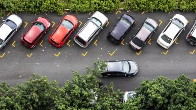 Estacionamento diagonal sem vagas disponíveis e um carro andando na rua ao lado.