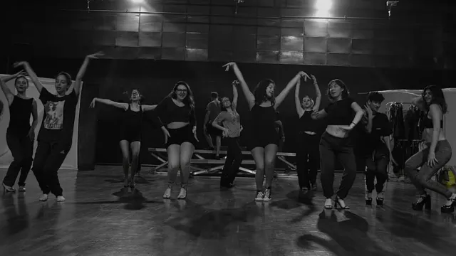 Fotografia em preto e branco, com grupo de estudantes do curso de Teatro da UFU dançando em um palco