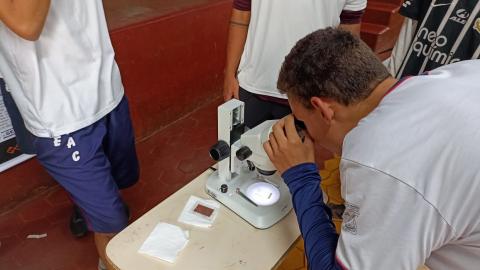 Participante do evento de geologia faz análise por meio de microscópio