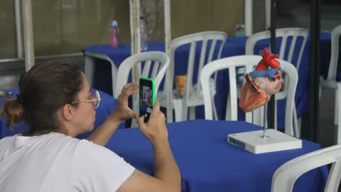 Pesquisadora tirando foto de maquete de coração