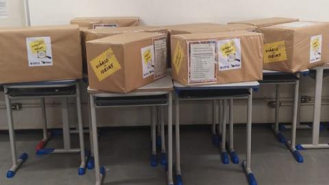 Imagem de caixas contendo os kits dispostas sobre mesas em uma sala