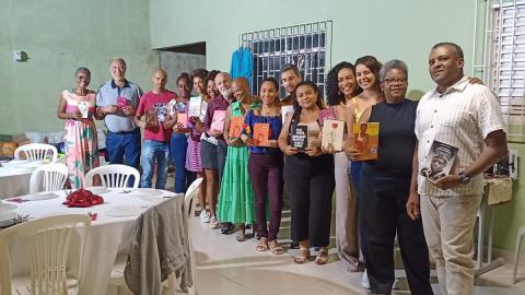 Na imagem, pessoas em pé segurando livro de autores negros.