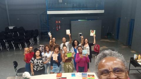 Na imagem, pessoas em pé segurando livro de autores negros.