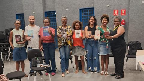 Na imagem, pessoas em pé segurando livro de autores negros.