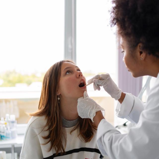 Mulher profissional de saúde colhendo amostra salivar de paciente mulher